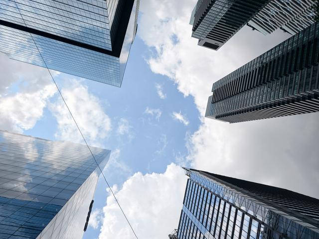 Vista hacia arriba de un grupo de edificios modernos bajo un cielo nublado.