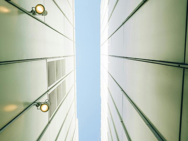 La imagen muestra una perspectiva desde el suelo hacia el cielo entre dos edificios altos y delgados.