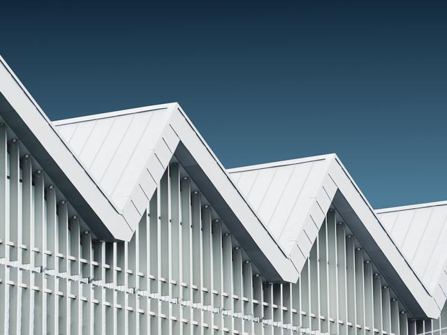 La imagen muestra un edificio con un diseño moderno y techos en forma de zigzag.