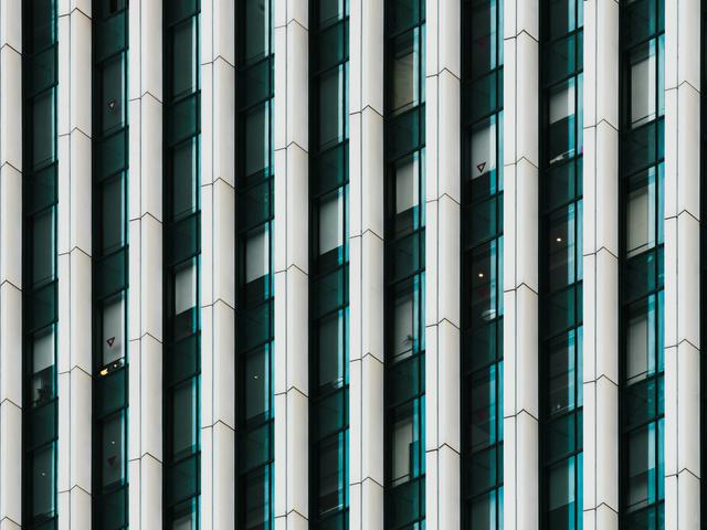 Primer plano de una fachada de un edificio moderno con patrones geométricos en cristal y metal.