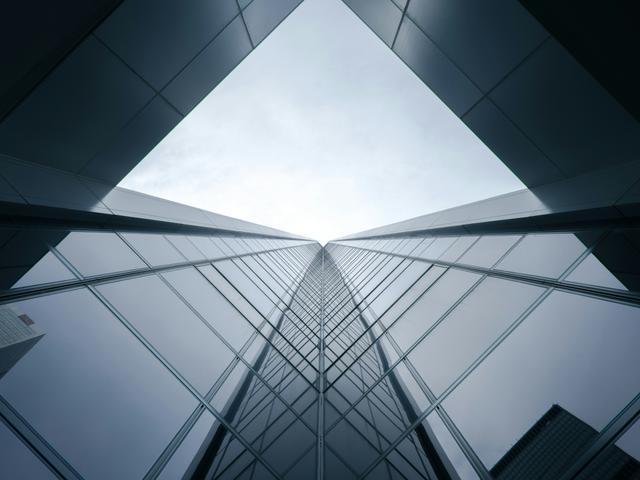 La imagen muestra una vista en ángulo de un rascacielos de cristal que apunta hacia el cielo.