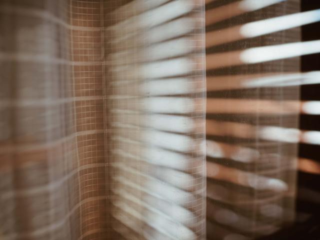 Imagen abstracta de luz filtrándose a través de persianas sobre una superficie texturizada.