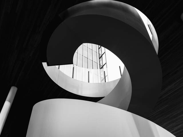 La imagen muestra una escalera en caracol con un diseño moderno y elegante en blanco y negro.
