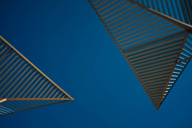 La imagen muestra una perspectiva de estructuras angulares con un fondo de cielo azul claro.