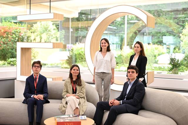 Cinco personas posan en un ambiente moderno y luminoso, rodeados de plantas y una decoración contemporánea.