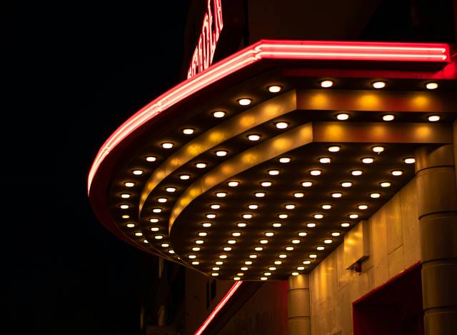 Una marquesina iluminada de un cine en la noche.