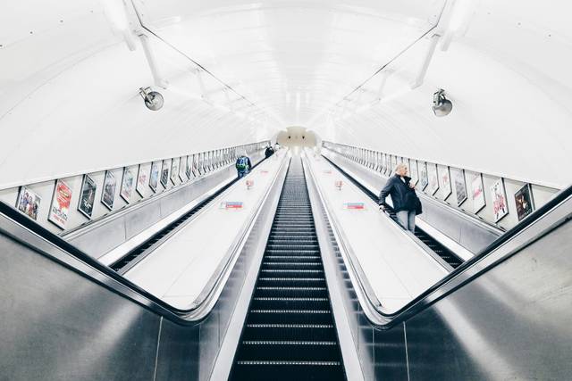 Una vista de una escalera mecánica en una estación de metro con personas subiendo y bajando.