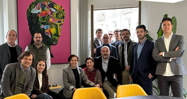 Un grupo de personas se reúne en una sala con un fondo artístico colorido.