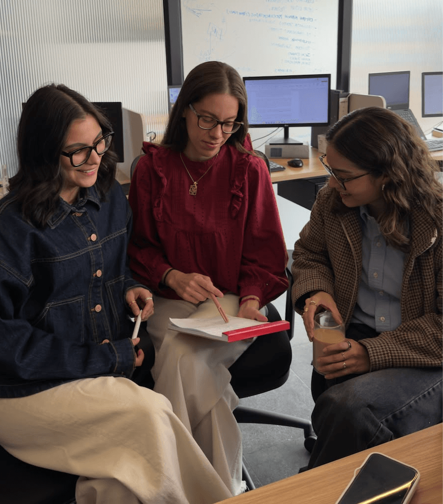 Tres mujeres se reúnen en un ambiente de trabajo colaborando en un proyecto.