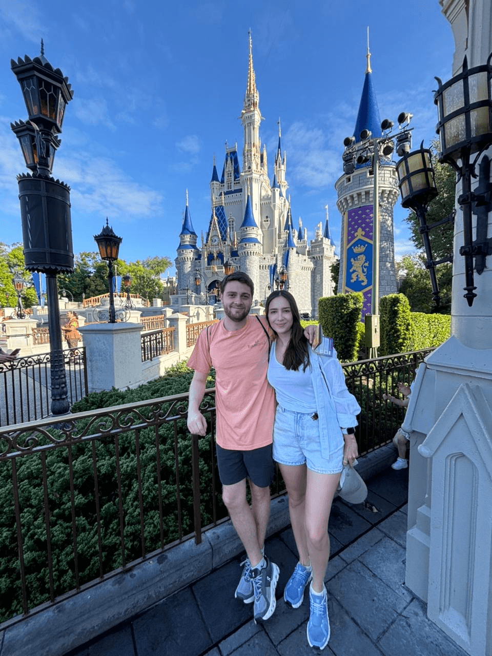 Una pareja sonriente posa frente a un castillo en un parque temático.