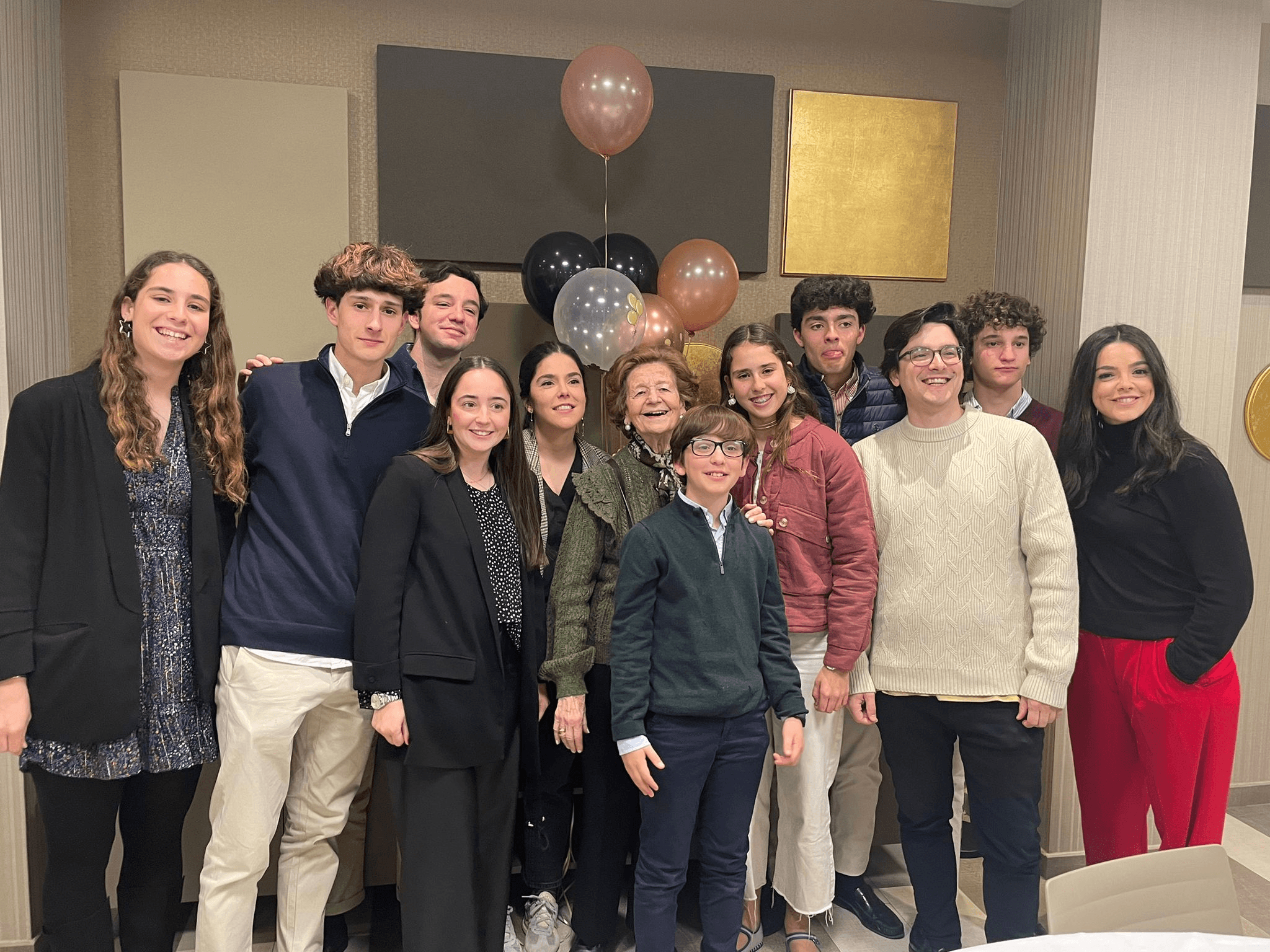 Un grupo de personas sonrientes posando juntas en una celebración con globos de fondo.
