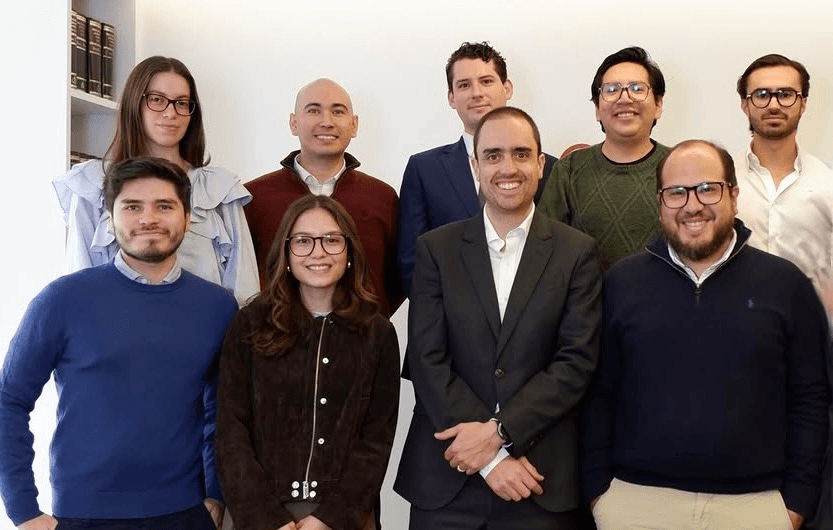 Un grupo de nueve personas sonríen en una foto en un entorno de oficina.