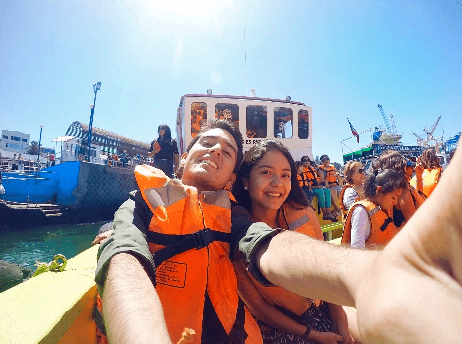 Una pareja sonriente se toma un selfie en un bote mientras usan chalecos salvavidas.