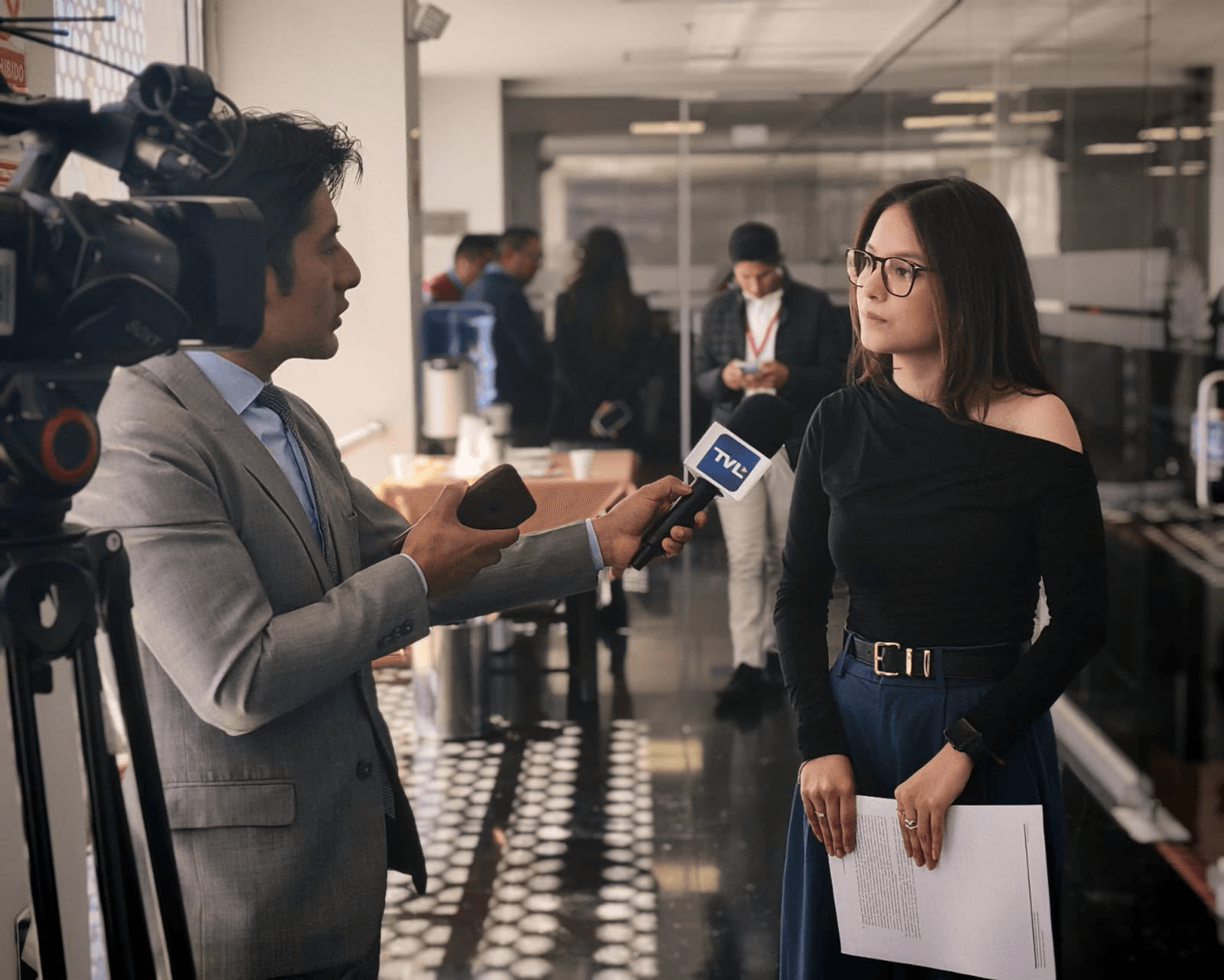 Un periodista entrevista a una mujer en un entorno profesional.