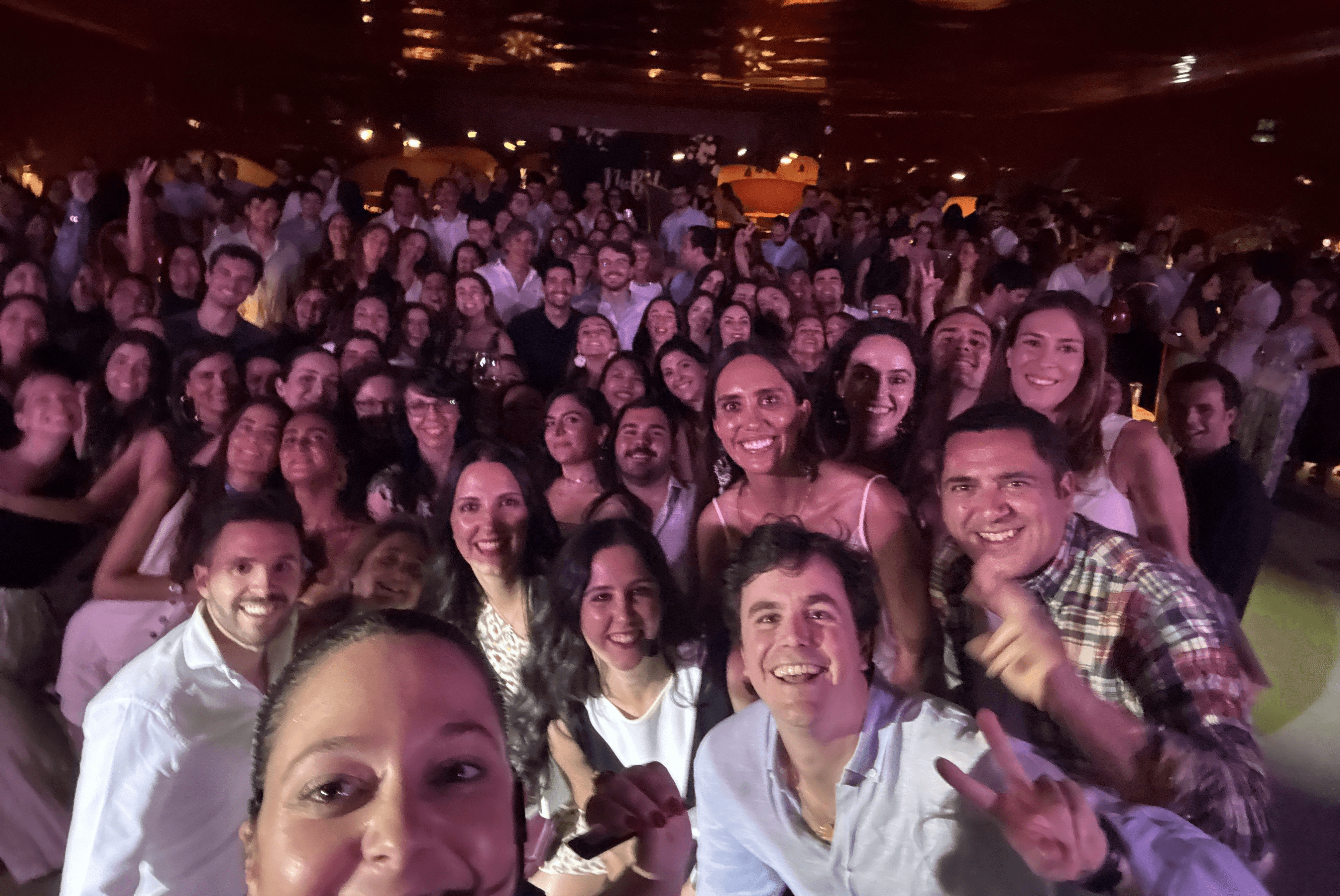 Una gran multitud de personas sonrientes se agrupan para una selfie en un ambiente festivo.